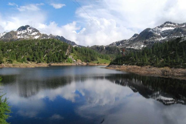 Uno stupendo paesaggio montano, col suo cielo in un momento di sereno, si specchia alla perfezione in un cristallino lago di montagna.